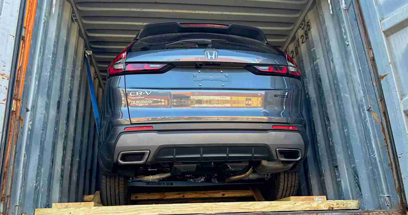 Rear view of a blue Honda CR-V secured inside a metal shipping container, seen from the back. 1≤2≤3 (trim as needed).