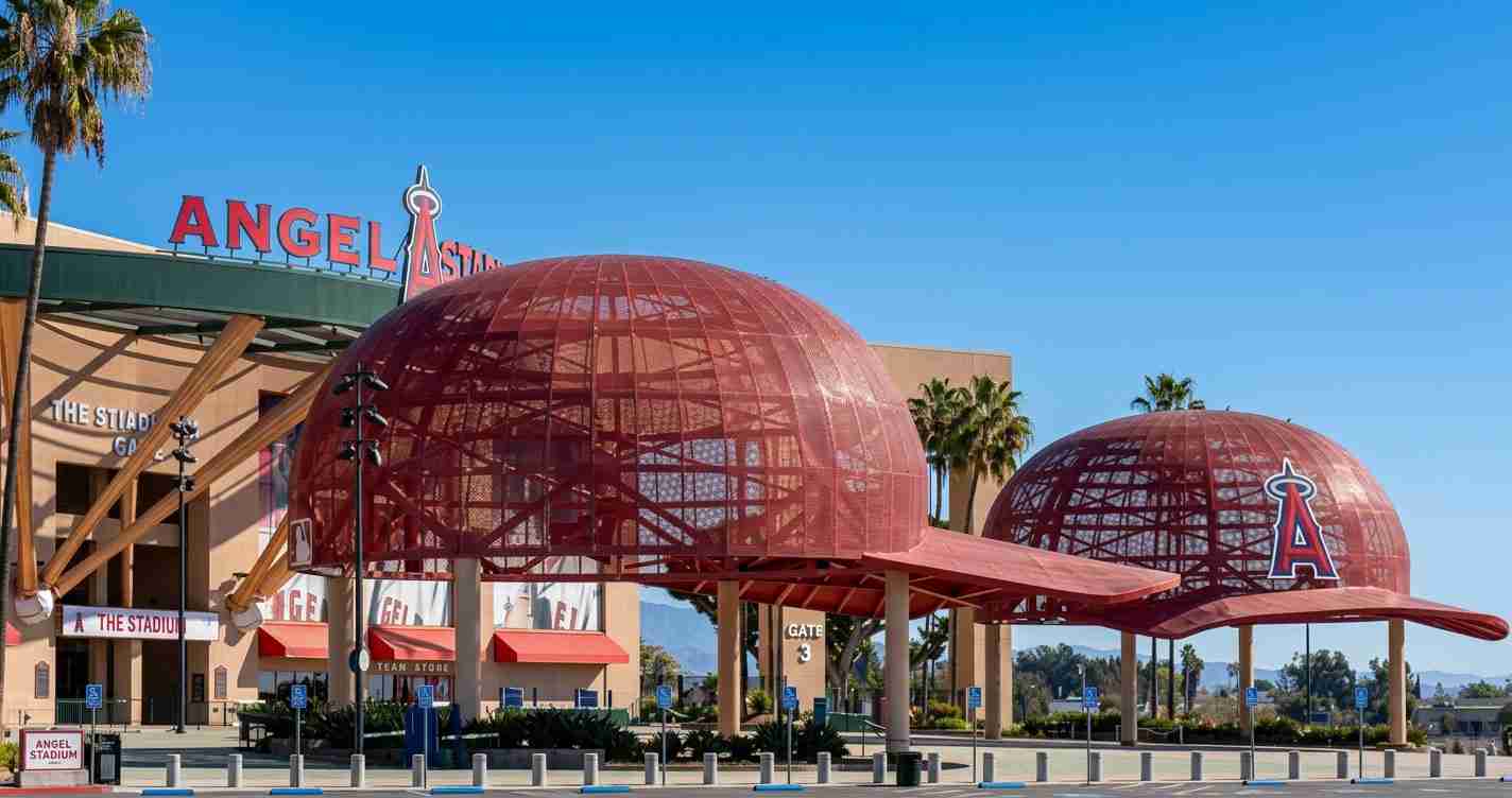 Exterior of Angels Stadium with red dome structures and a large Angels 'A' logo under a bright blue sky.