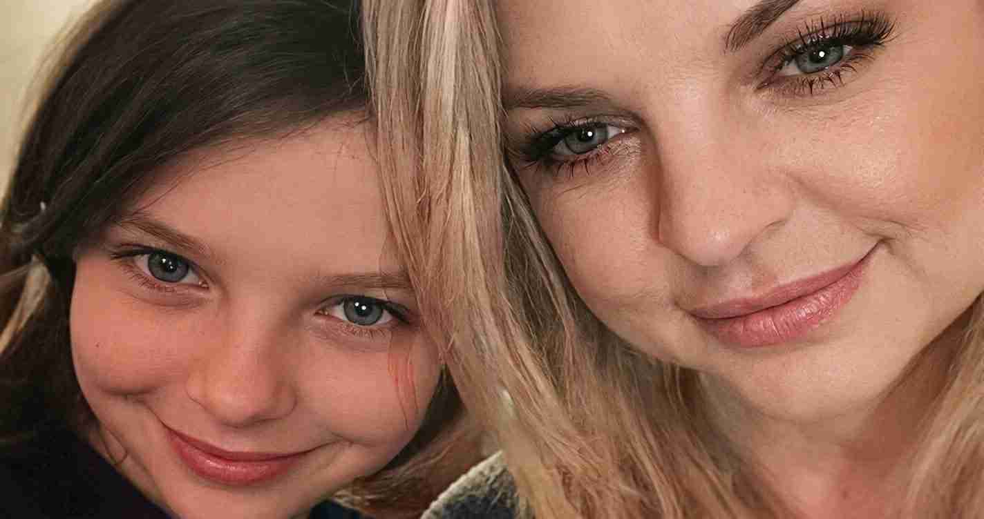 Close-up of two smiling people leaning in together, showing their faces and blue eyes.