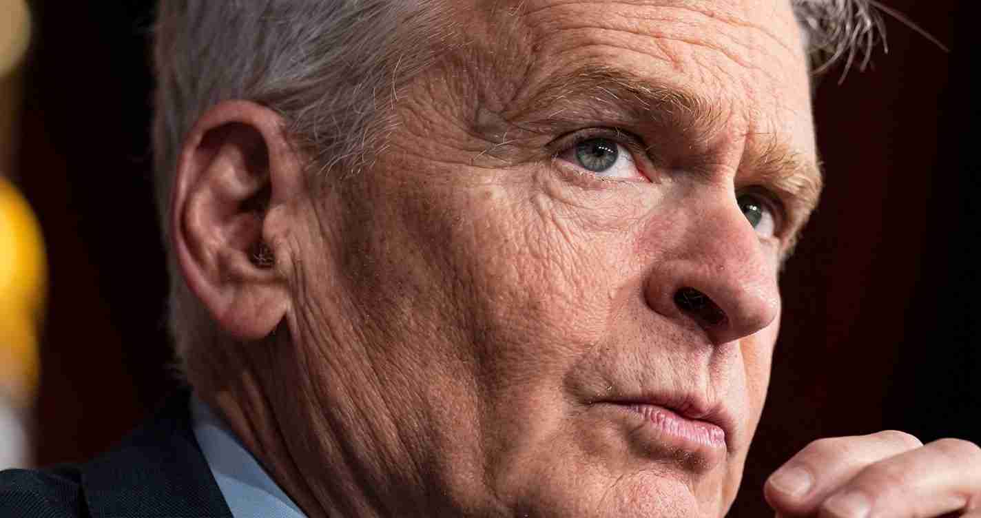 Close-up of a mature man with gray hair and blue eyes, looking pensively to the right.