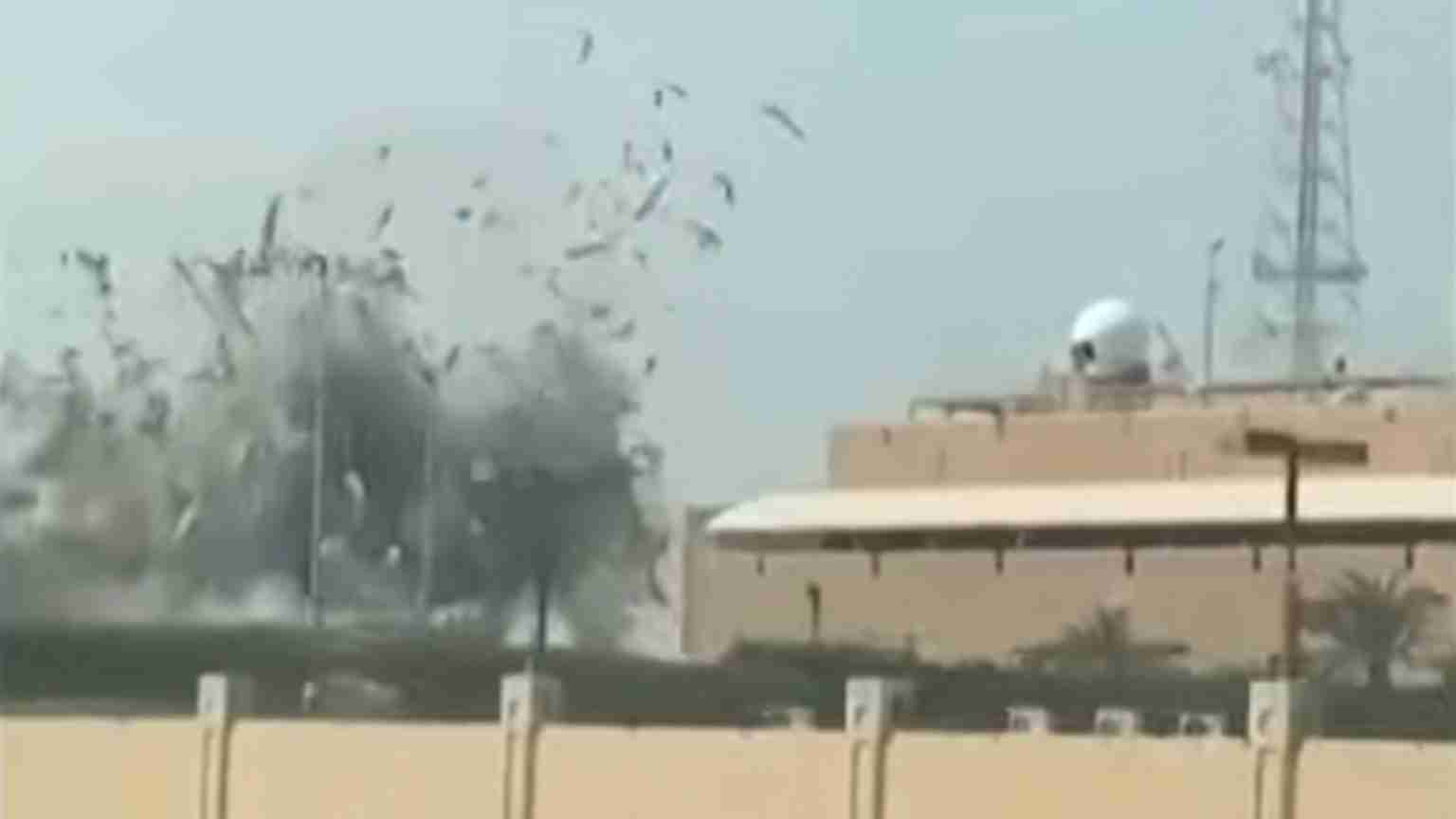 Desert military base with a beige building and dome radar; explosion and smoke rising on the left side of the scene.