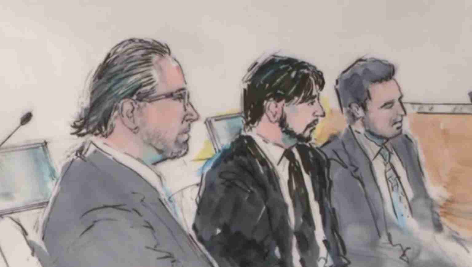 Three men in suits sitting side by side in a panel, likely a courtroom setting, listening attentively.