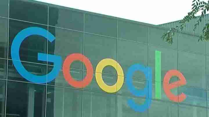 Google logo displayed on the glass exterior of a modern office building, with colorful letters in blue, red, yellow, blue, green, and red across the facade