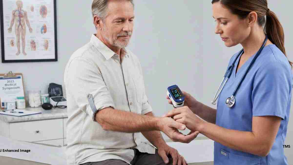 Nurse in blue scrubs uses a handheld monitor while a patient’s left arm is wrapped with a blood pressure cuff in a clinic examination room.