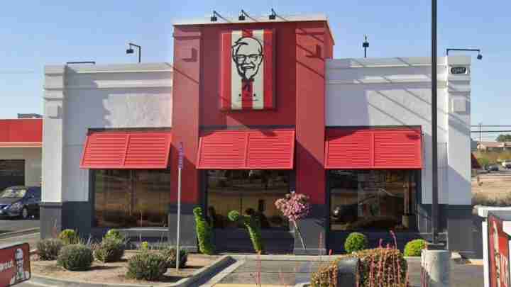 KFC restaurant exterior with a red facade, red awnings, and a Colonel Sanders sign above the entrance.
